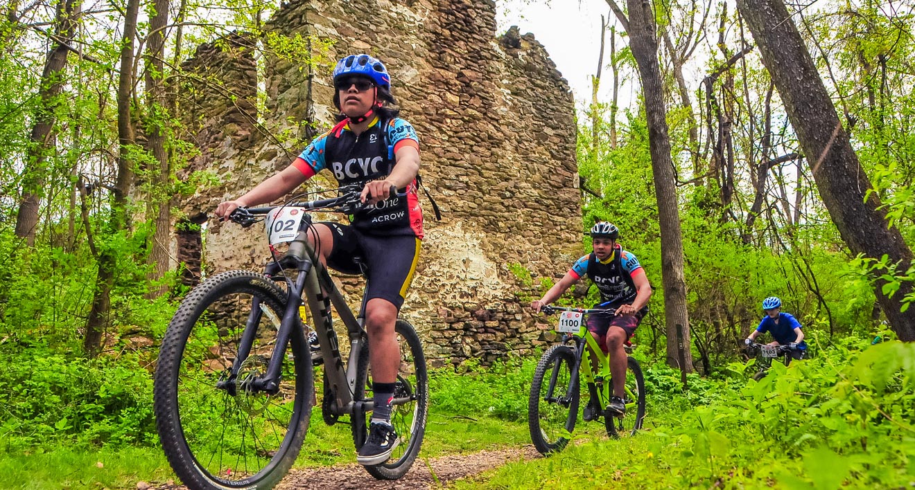 A group of people riding bikes on a trail in the woods
Description automatically generated